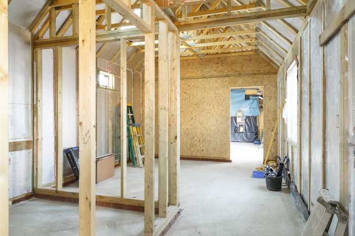 This is a picture of an unfinished extension, letting in a lot of light, with a wooden structure in place ready for internal walls, and exposed wall insulation before being plaster boarded