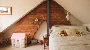 A converted loft bedroom with an exposed brick chimney breast and sloping ceiling, a loft conversion designed by Maidenhead Planning.