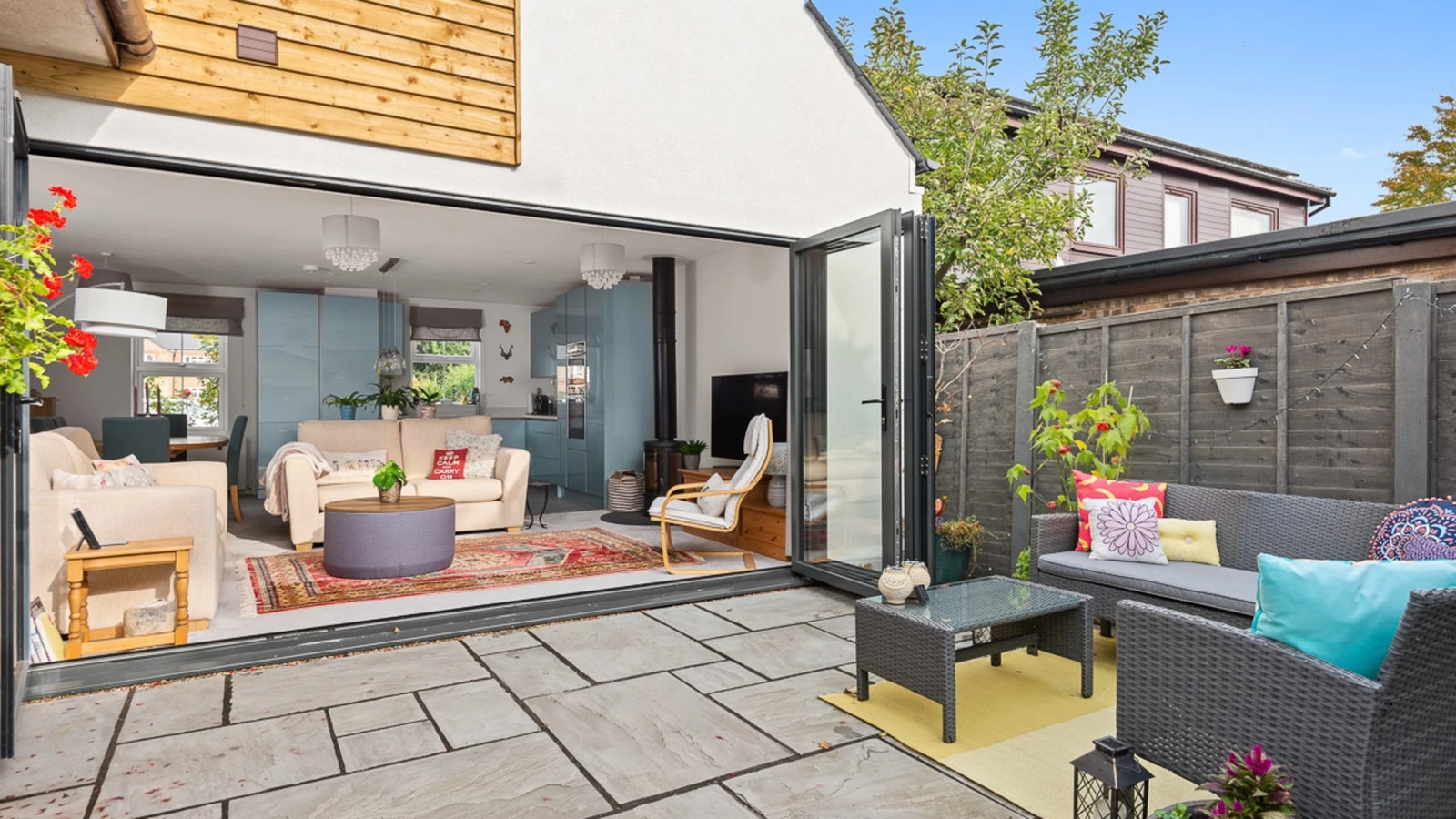 Completed rear extension with cedar cladding and bifold doors open onto a paved patio and garden seating