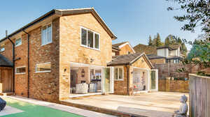 Rear of a brick house with a single-storey extension and open bi-fold doors leading onto a patio, a home extension project by Maidenhead Planning