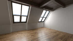 Empty loft room with slanted windows and wooden floor.