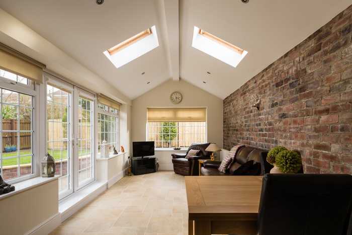 This is a picture of a completed extension. Letting in lots of light with patio doors leading to a garden and a stylish exposed brick feature wall