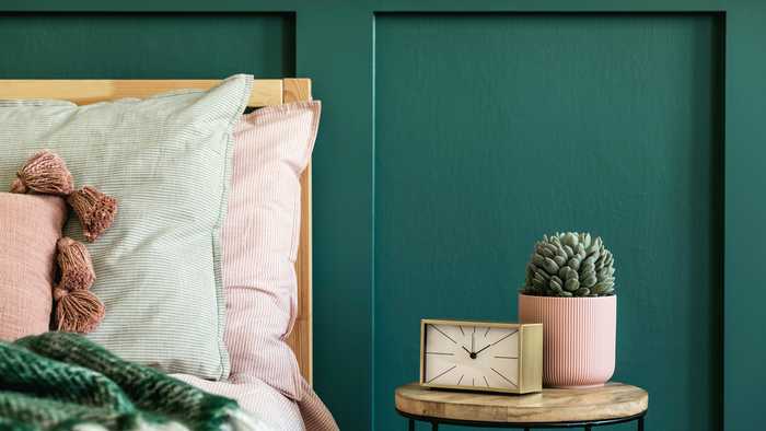 Stylish bedroom with a bed, coffee table with a succulent plant and alarm clock. 