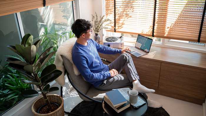 Person working from home in a casual office space with swivel chair, houseplants and minimalist desk