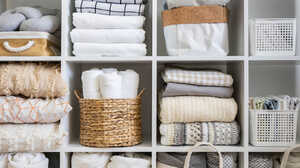 Organized shelves displaying neatly folded towels and textured blankets in neutral tones.
