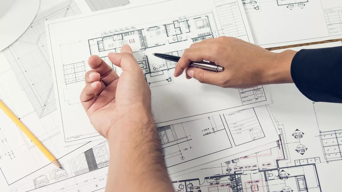 Architectural plans for a home extension spread out during an early design discussion