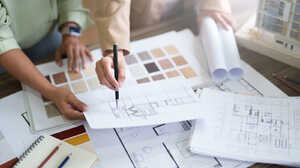 Two people reviewing floor plans alongside a board of material and colour swatches and rolled drawings