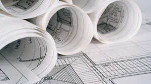 Rolled architectural drawings resting on an unrolled technical drawing of a building