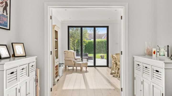 Bright entryway leading to a cozy sitting room with large windows and light wood flooring.