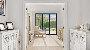 Bright hallway leading to a cozy room with chairs and glass doors opening to a garden.