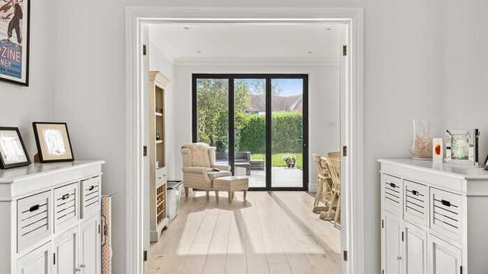 Bright entryway leading to a cozy sitting room with large windows and light wood flooring.