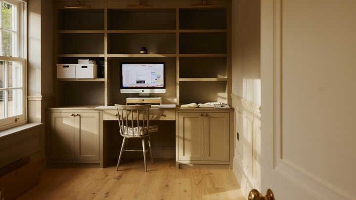 Minimalist home office with a computer, desk, bookshelves, and natural light.
