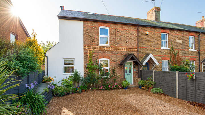 Charming Maidenhead Cottage with extension, a garden and gravel driveway in sunny weather.