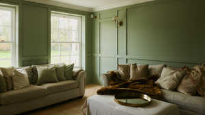 Cozy living room with green walls, two sofas, and a coffee table with a tray.