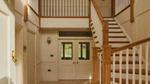 Bright dining area with a wooden table, blue chairs, and large glass windows overlooking a garden.