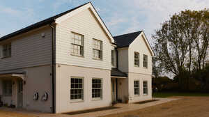 Bright dining area with a wooden table, blue chairs, and large glass windows overlooking a garden.
