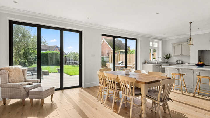 Modern kitchen and dining area with large windows and wooden furniture.