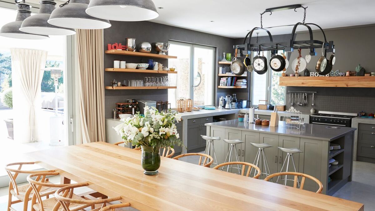 Open-plan kitchen with a long oak dining table, pendant lights, grey island and open shelving