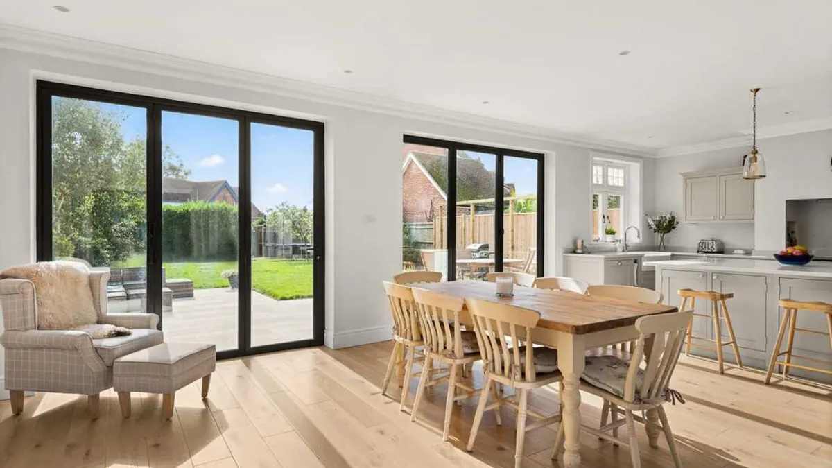 Open-plan kitchen and dining room with black framed sliding doors onto the garden