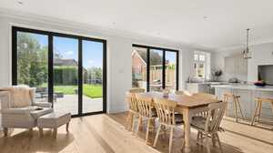 Open-plan kitchen and dining room with black framed sliding doors onto the garden