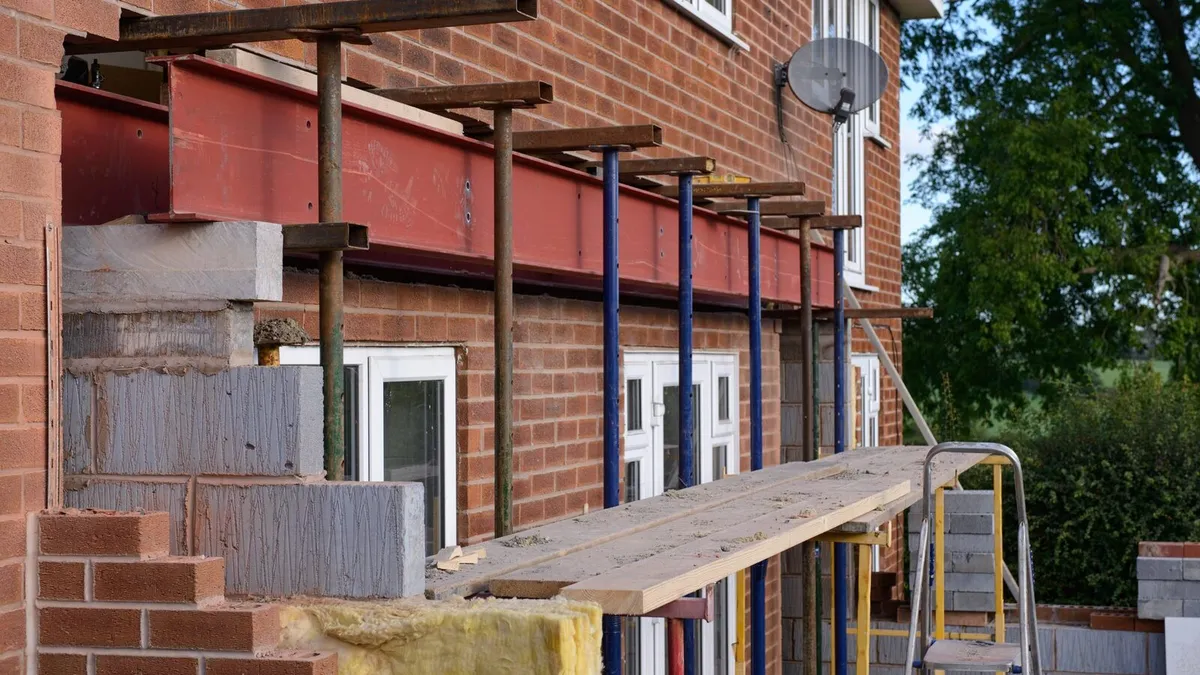 Rear extension build with a red steel beam on props, new blockwork and brick walls