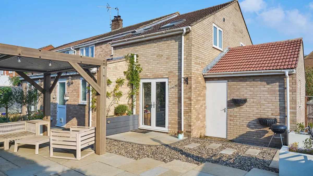 Rear of a brick semi-detached house with French doors, a timber pergola and a paved patio