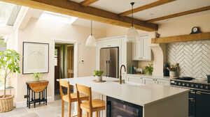 Modern kitchen with wood beams, a large island, and two stools; bright and spacious design.