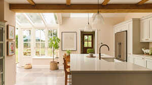 Bright modern kitchen with a large island, natural light, and a view of a glass conservatory.